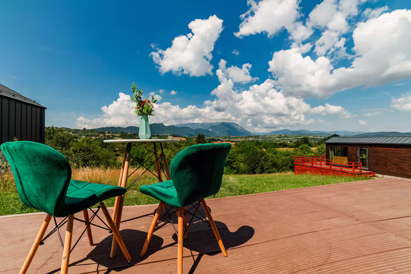 Zonă de relaxare pe terasa cabanei SkyAtlas Hideaway, cu fotolii verzi și vedere spre pădure Zonă de relaxare pe terasa cabanei SkyAtlas Hideaway, cu fotolii verzi și vedere spre pădure