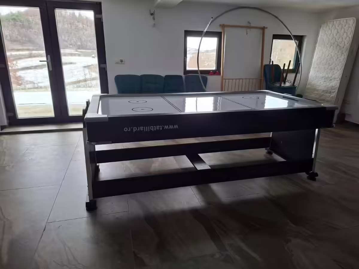Copil jucând air hockey în spațiul de joacă interior al cabanei