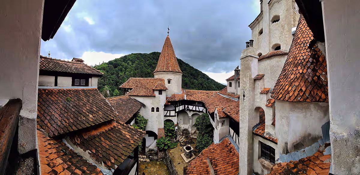 Castelul Bran cu acoperișuri roșii și pădure întunecată în fundal Castelul Bran cu acoperișuri roșii și pădure întunecată în fundal