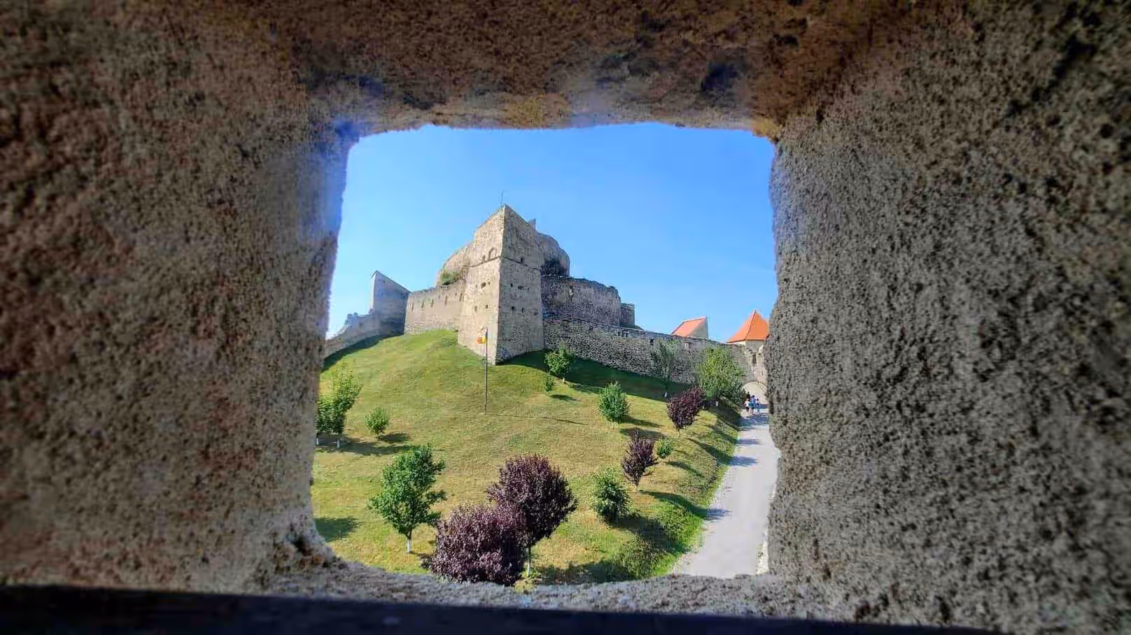 Cetatea Rupea încadrată de o fereastră din zidul de piatră