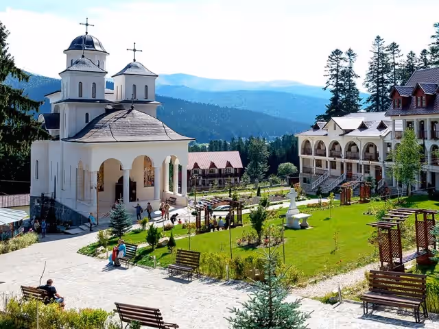Biserica Mănăstirii Caraiman și grădina cu bănci, vara Biserica Mănăstirii Caraiman și grădina cu bănci, vara