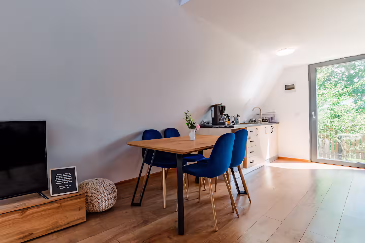 Masă pentru patru persoane și televizor în cabana A-frame SkyAtlas Hideaway Masă pentru patru persoane și televizor în cabana A-frame SkyAtlas Hideaway