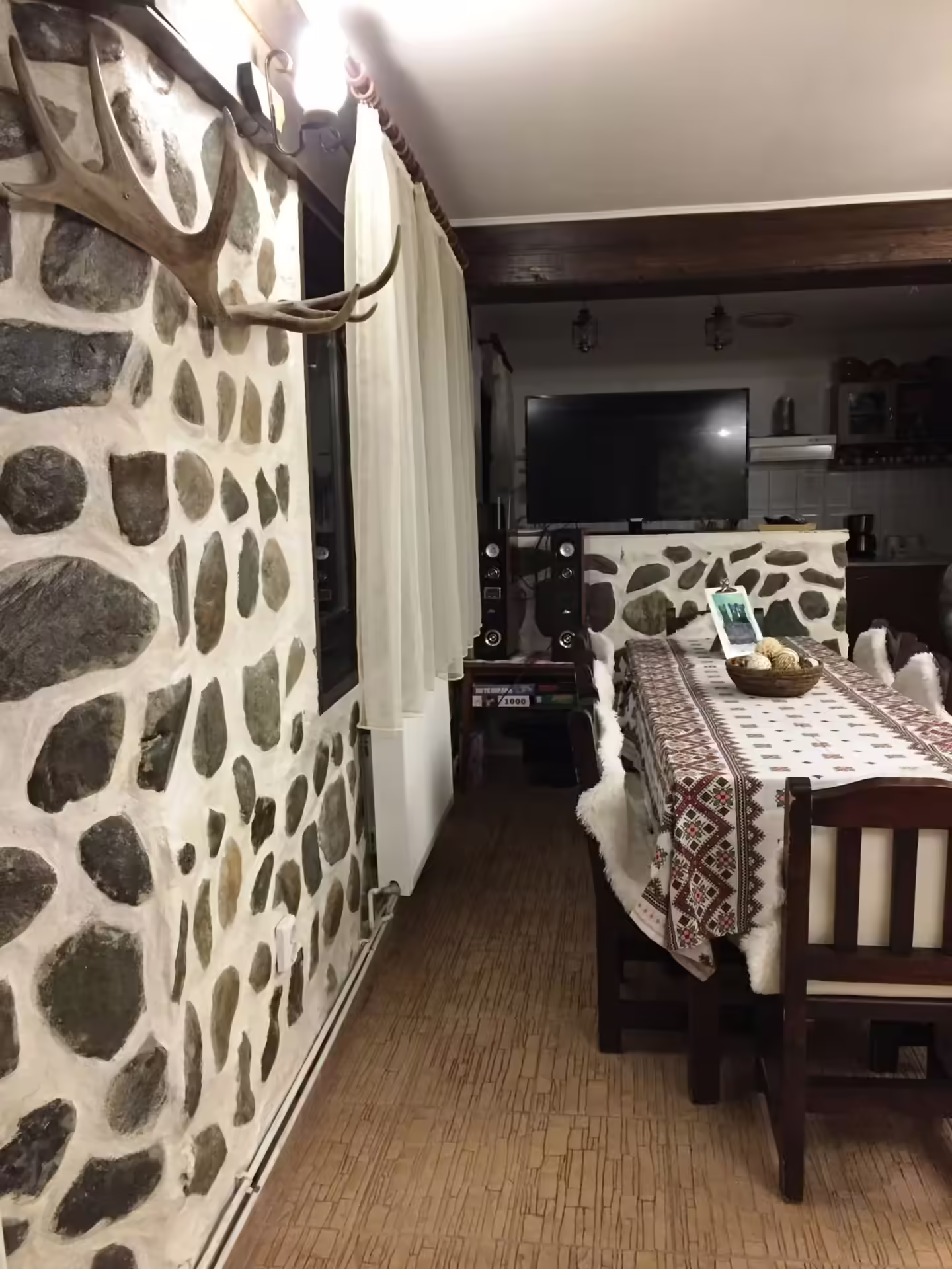 Salon cu perete din piatră și masă de mese la Casa Haiducilor Sătic, Rucăr Salon cu perete din piatră și masă de mese la Casa Haiducilor Sătic, Rucăr