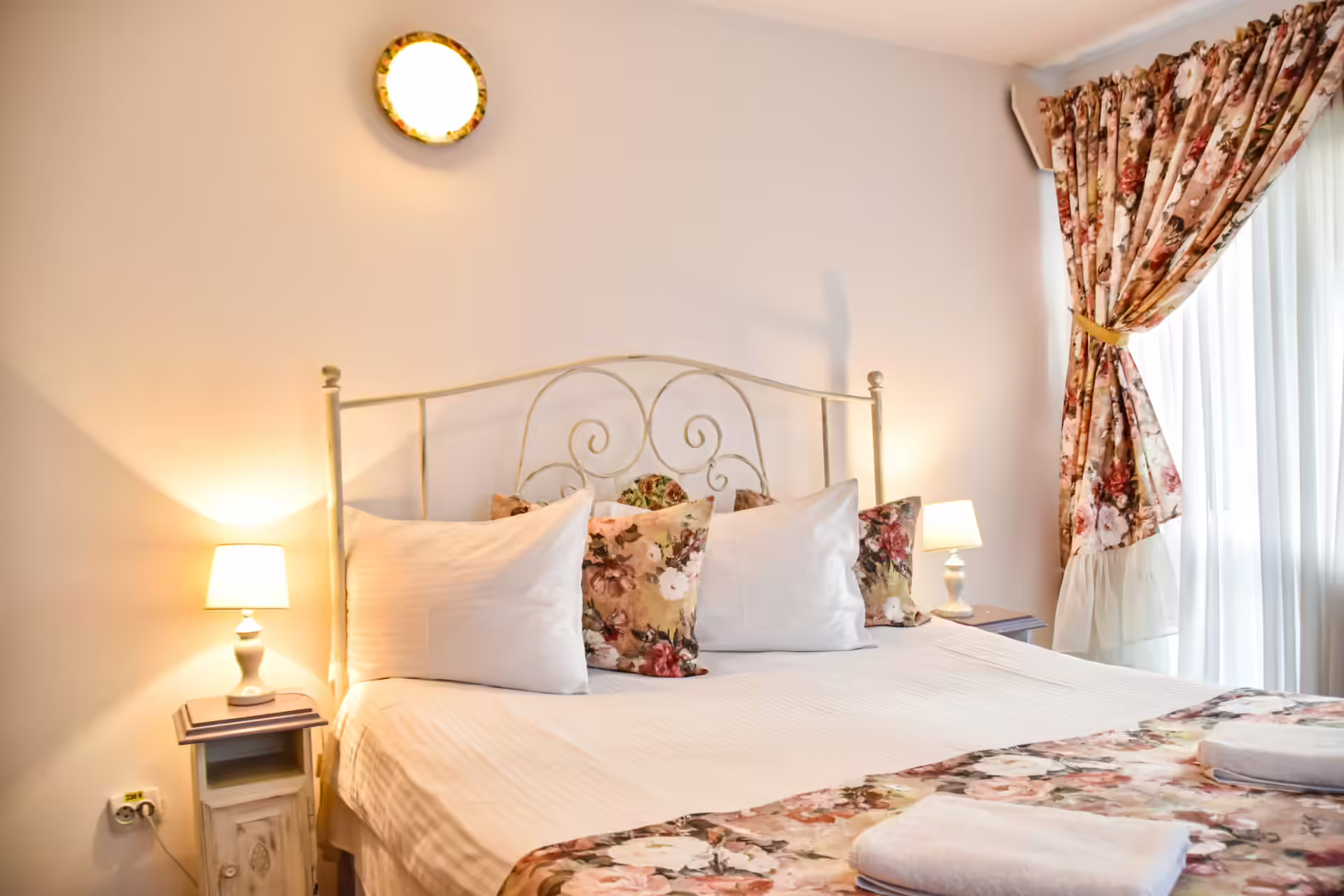 Dormitor matrimonial cu veioze și draperii la Casa Georgea