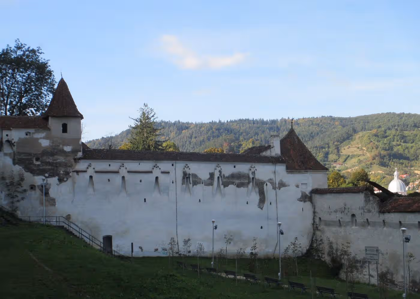 Zidurile albe ale Bastionului Țesătorilor și dealurile din jurul Brașovului