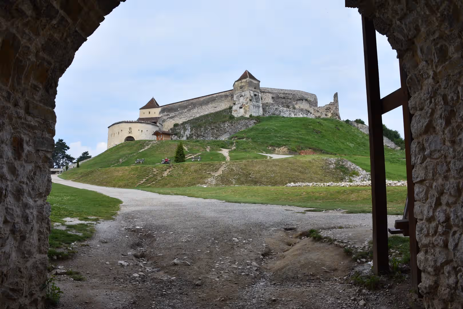 Cetatea Râșnov văzută printr-o poartă boltită, pe dealul verde Cetatea Râșnov văzută printr-o poartă boltită, pe dealul verde
