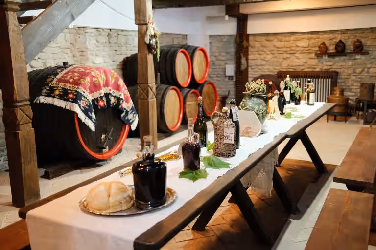 Butoaie de vin și masă cu ștergar în crama Muzeului Crama 1777 Butoaie de vin și masă cu ștergar în crama Muzeului Crama 1777