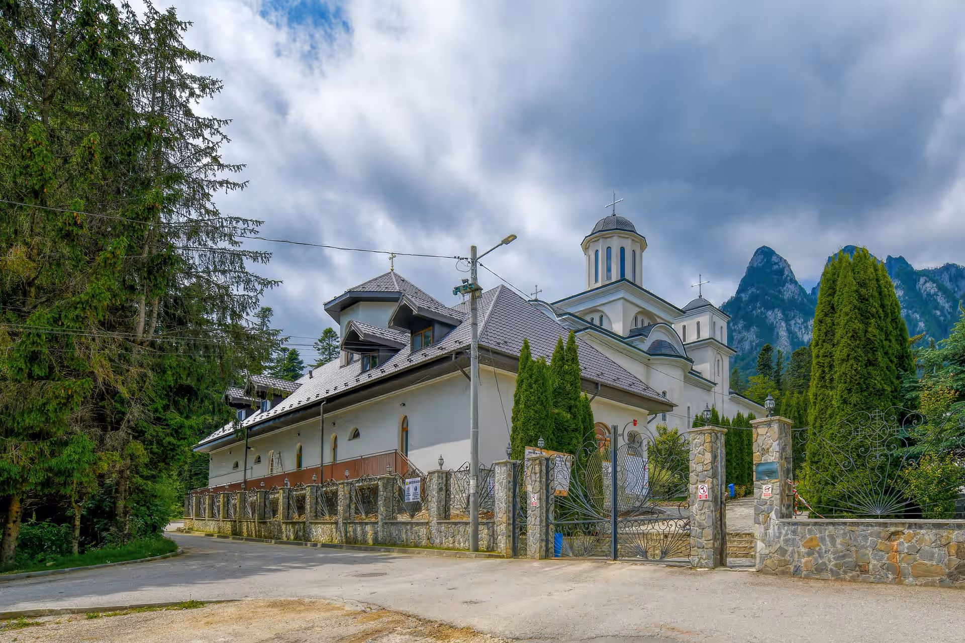 Intrarea în Mănăstirea Caraiman cu Munții Bucegi în fundal Intrarea în Mănăstirea Caraiman cu Munții Bucegi în fundal