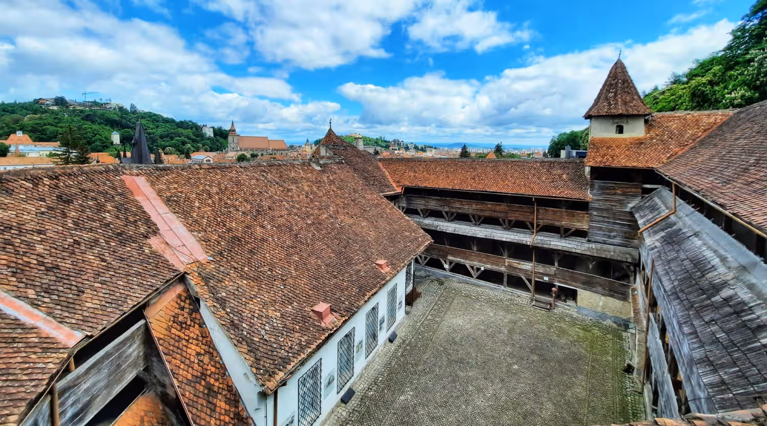 Curtea interioară a Bastionului Țesătorilor din Brașov, cu acoperișuri de țiglă și galerii din lemn