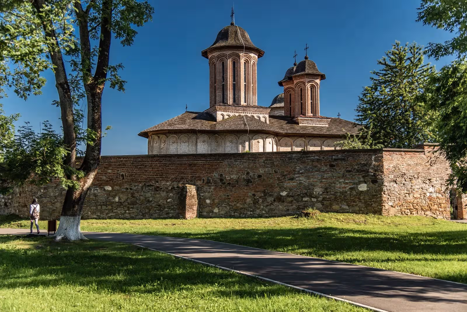 Zidul de incintă și biserica Mănăstirii Brebu văzute din parc