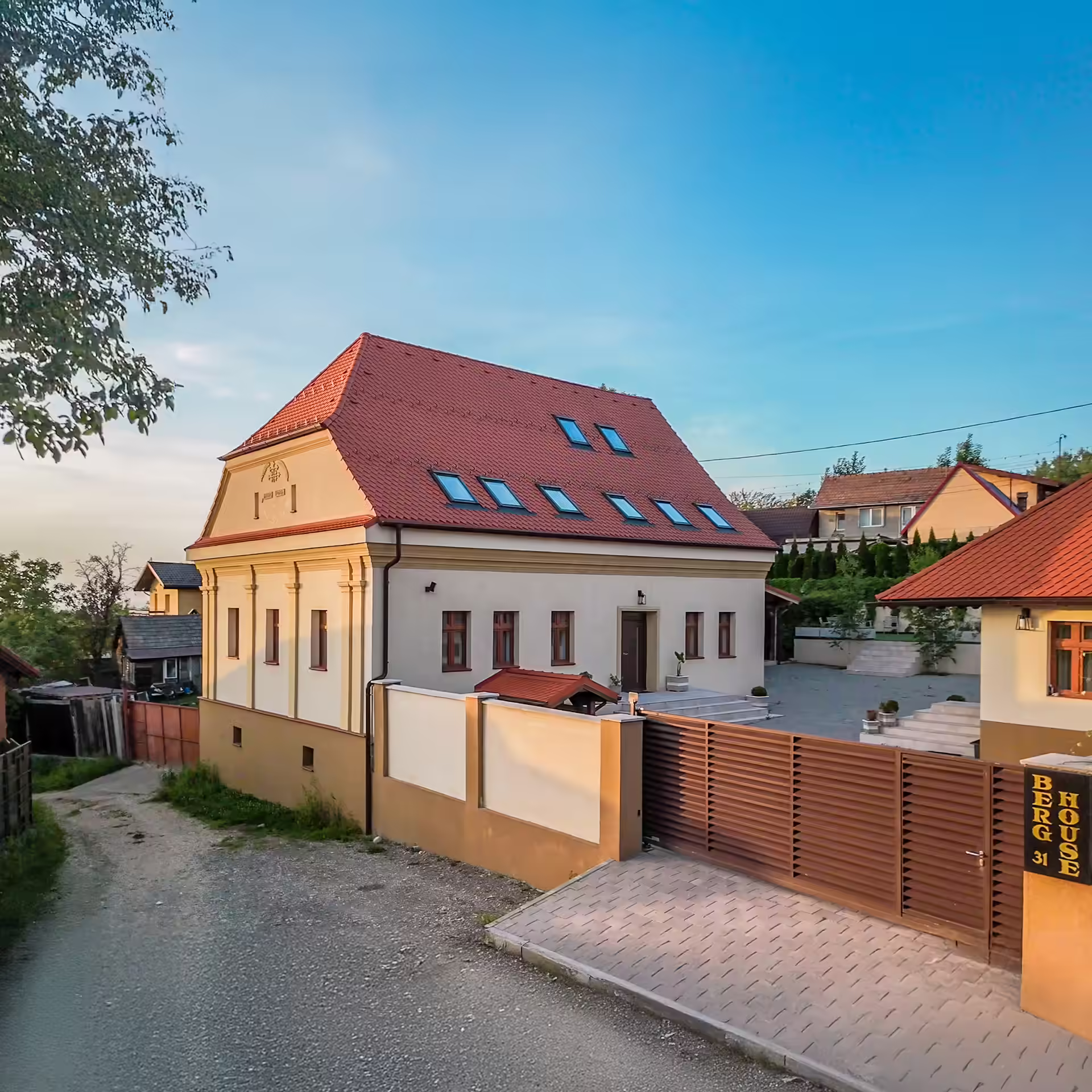 Berg House 31 Săcele, fațada vilei moderne văzută din stradă, cu poartă din lemn și acces auto Berg House 31 Săcele, fațada vilei moderne văzută din stradă, cu poartă din lemn și acces auto
