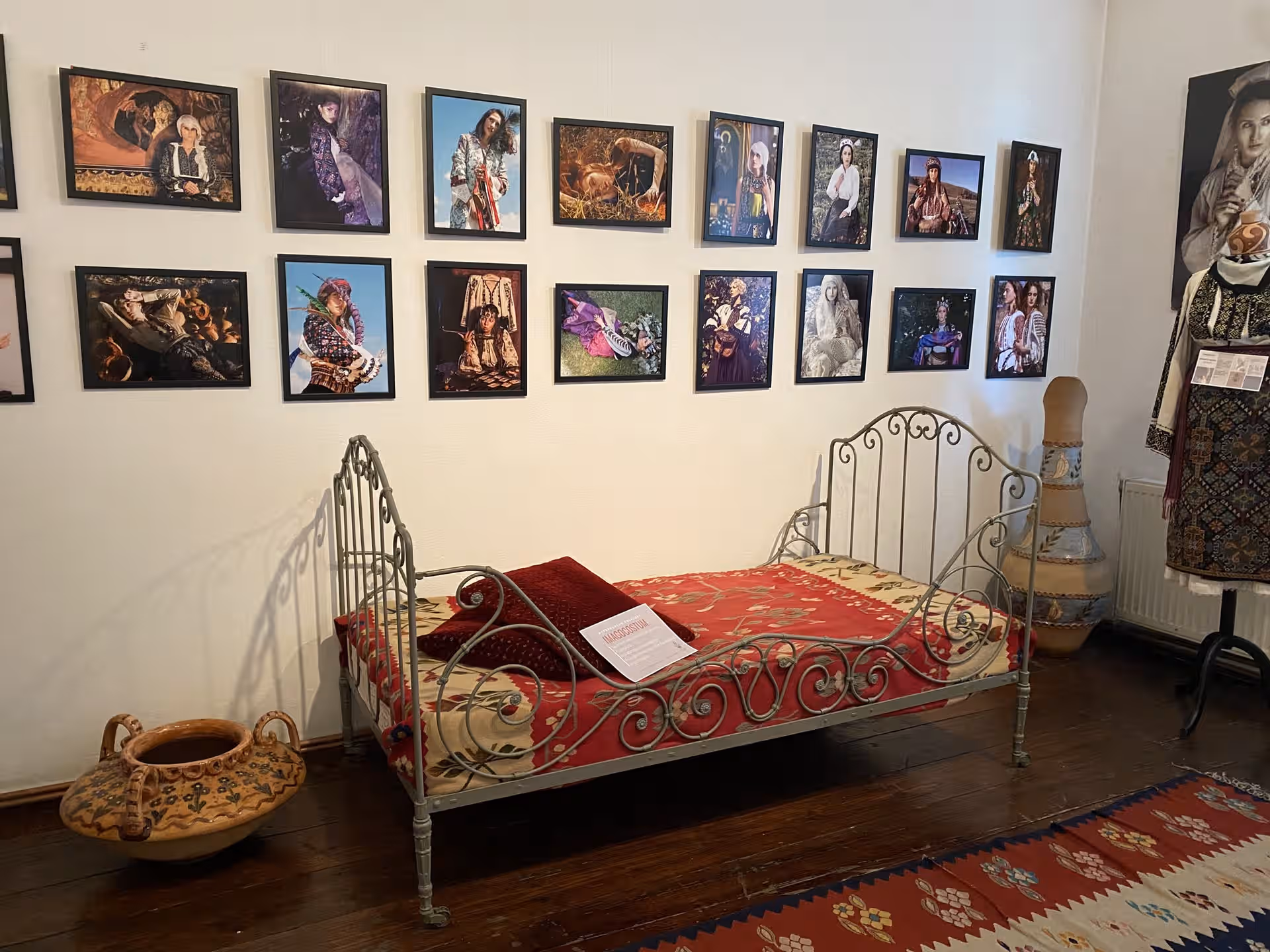 Dormitor cu pat de fier și tablouri în casa memorială Grigorescu