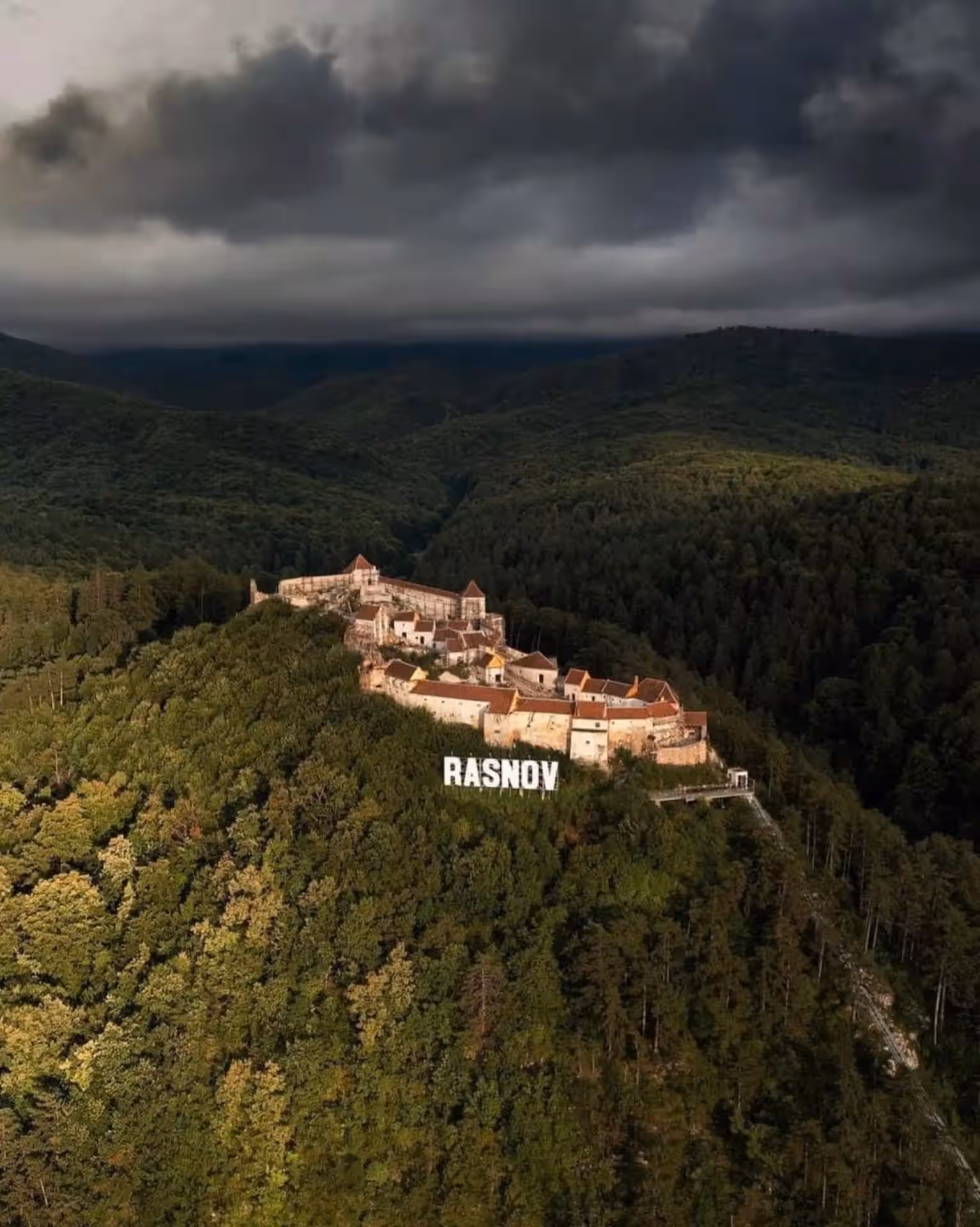 Cetatea Râșnov pe vârful dealului împădurit, vedere aeriană Cetatea Râșnov pe vârful dealului împădurit, vedere aeriană