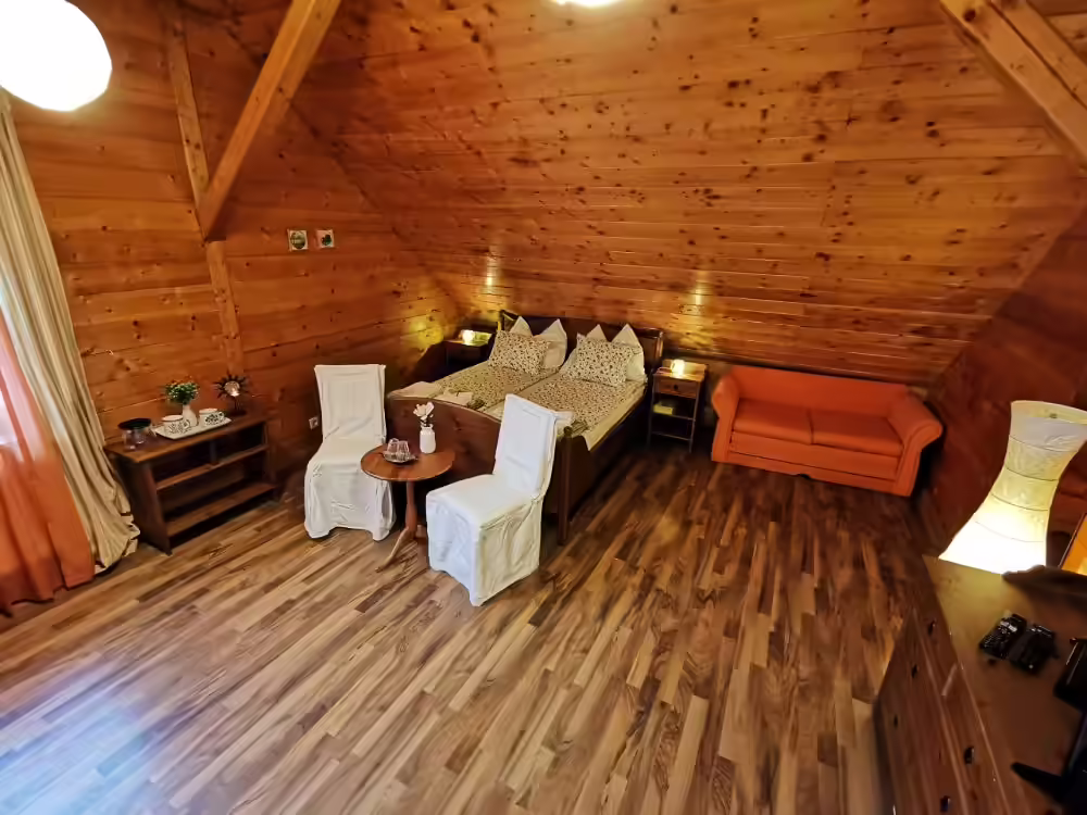 Cameră la mansardă cu pat matrimonial, canapea și pereți din lemn la Ohana Boutique Hotel