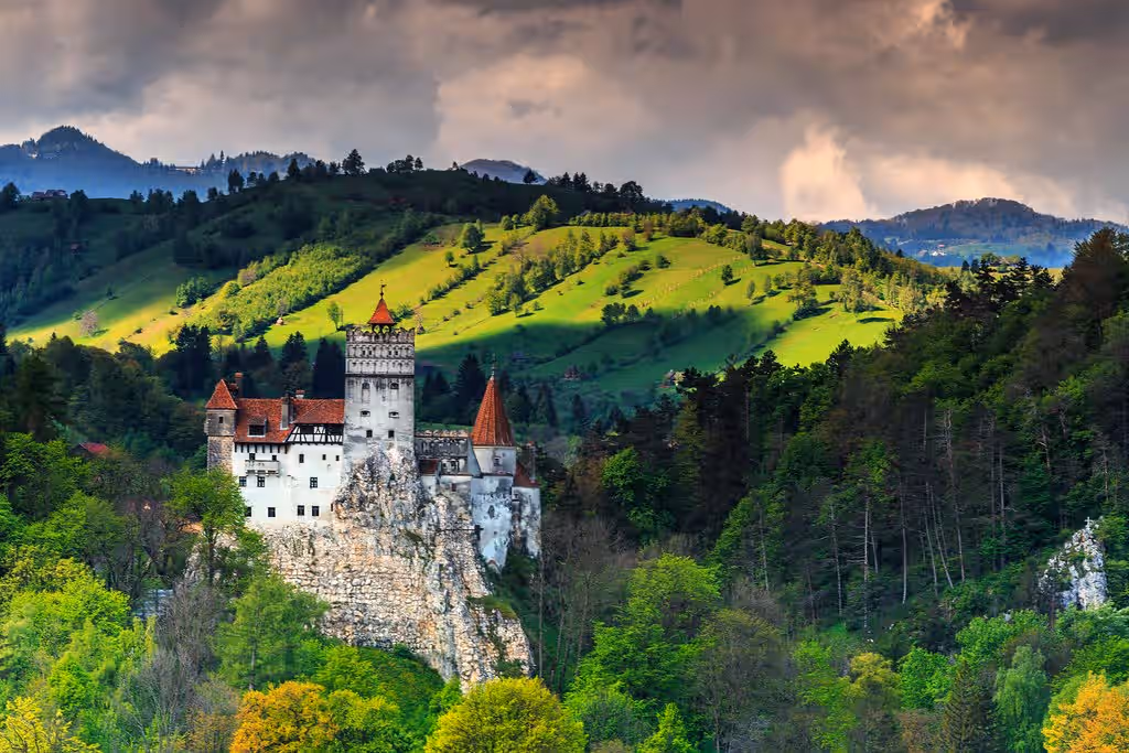 Castelul Bran cu acoperișuri roșii și pădure întunecată în fundal Castelul Bran cu acoperișuri roșii și pădure întunecată în fundal