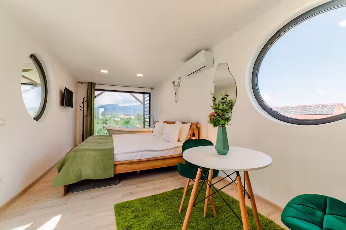 Interior luminos cu fereastră rotundă și vedere spre munți în cabana SkyAtlas Hideaway Interior luminos cu fereastră rotundă și vedere spre munți în cabana SkyAtlas Hideaway