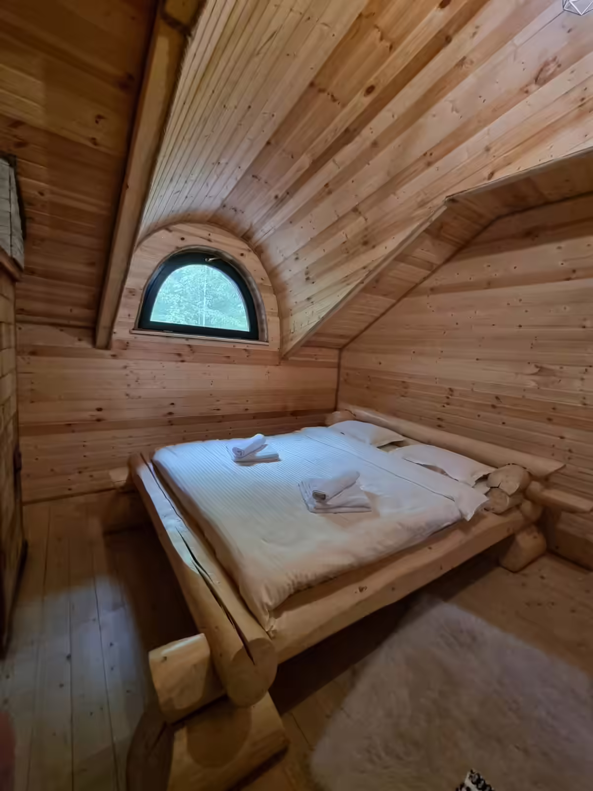 Dormitor cu pat dublu și fereastră rotundă la Mountain View Chalet Broșteni Dormitor cu pat dublu și fereastră rotundă la Mountain View Chalet Broșteni