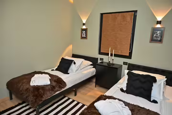 Dormitor cu două paturi și blănuri decorative la La Tulipe Noire