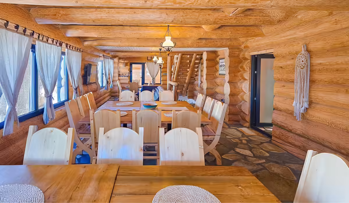 Zonă de dining cu masă lungă din lemn masiv la Cabana Alaska, Rânca