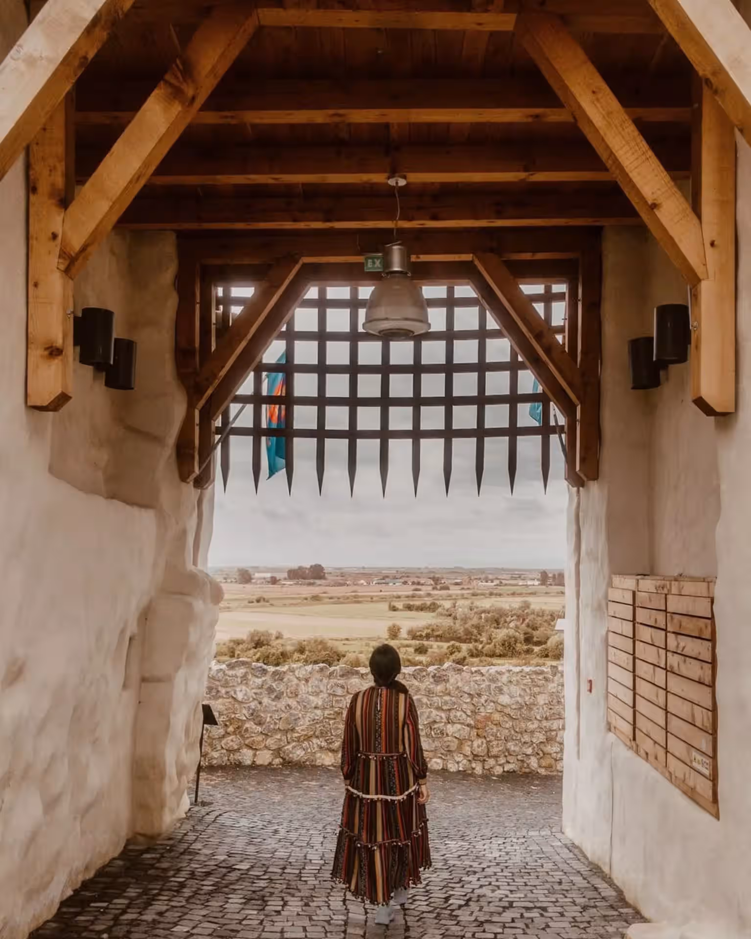 Poarta cu hersă a Cetății Feldioara, cu un vizitator în costum medieval Poarta cu hersă a Cetății Feldioara, cu un vizitator în costum medieval