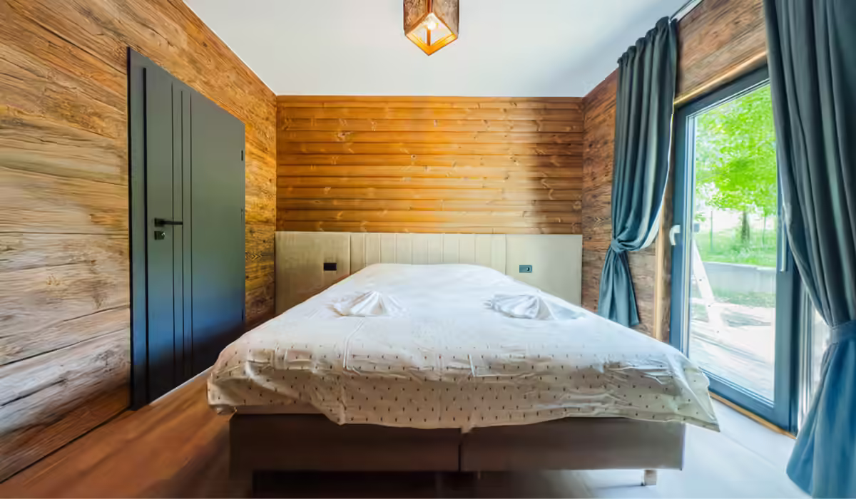 Dormitor cu pat dublu și pereți din lemn la AZA Chalet, Tohănița