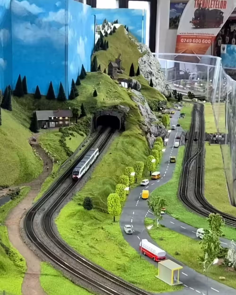 Tren în miniatură ieșind din tunel lângă o autostradă, expoziția Sinaia