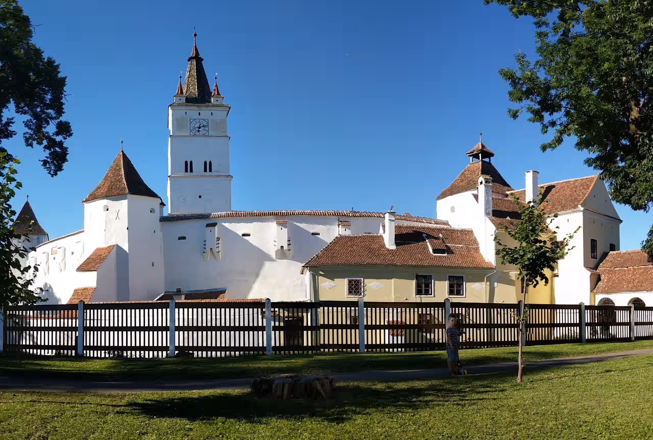 Biserica Fortificată Hărman cu gard de lemn și pajiște în față