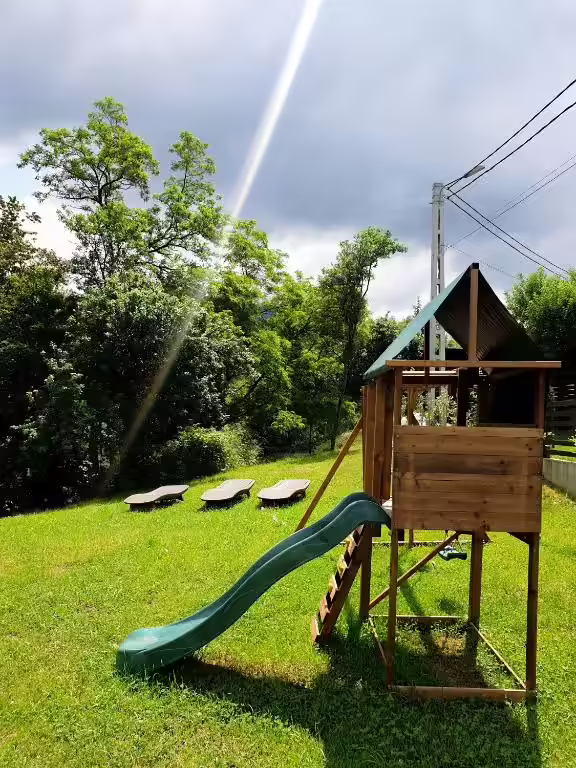 Loc de joacă pentru copii cu tobogan, pe gazonul pensiunii La Rusu