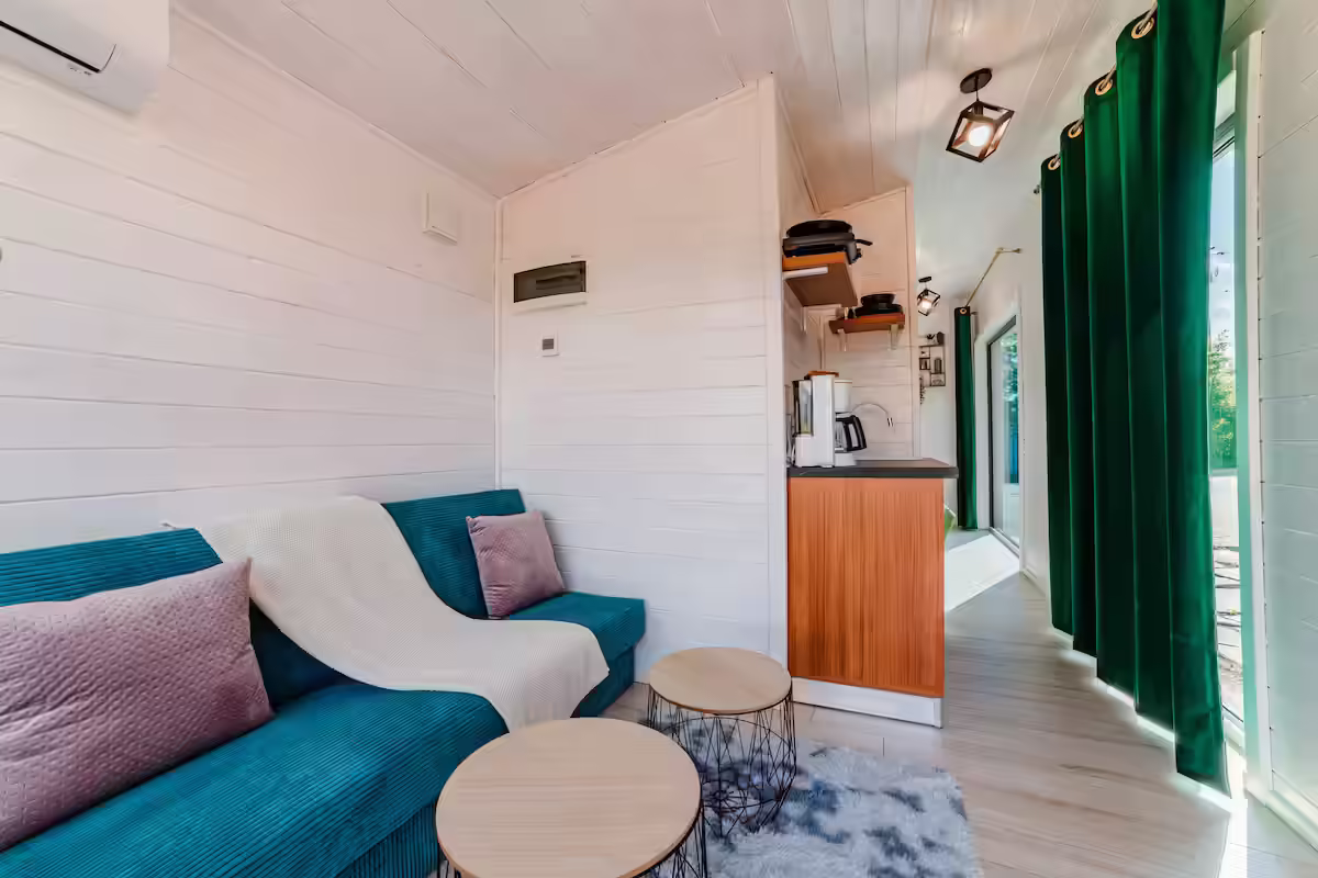 Living cu canapea turcoaz și chicinetă utilată în cabana SkyAtlas Hideaway din Sohodol Living cu canapea turcoaz și chicinetă utilată în cabana SkyAtlas Hideaway din Sohodol