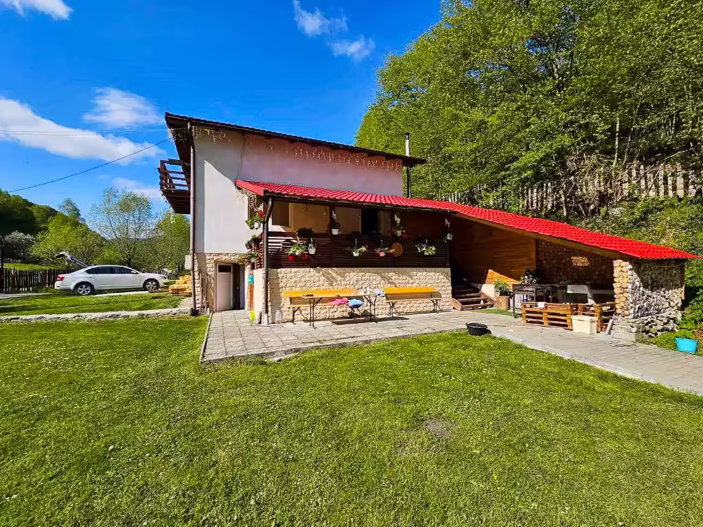 Exteriorul Di&D House din Bănița, județul Hunedoara, cu terasă acoperită și curte verde Exteriorul Di&D House din Bănița, județul Hunedoara, cu terasă acoperită și curte verde